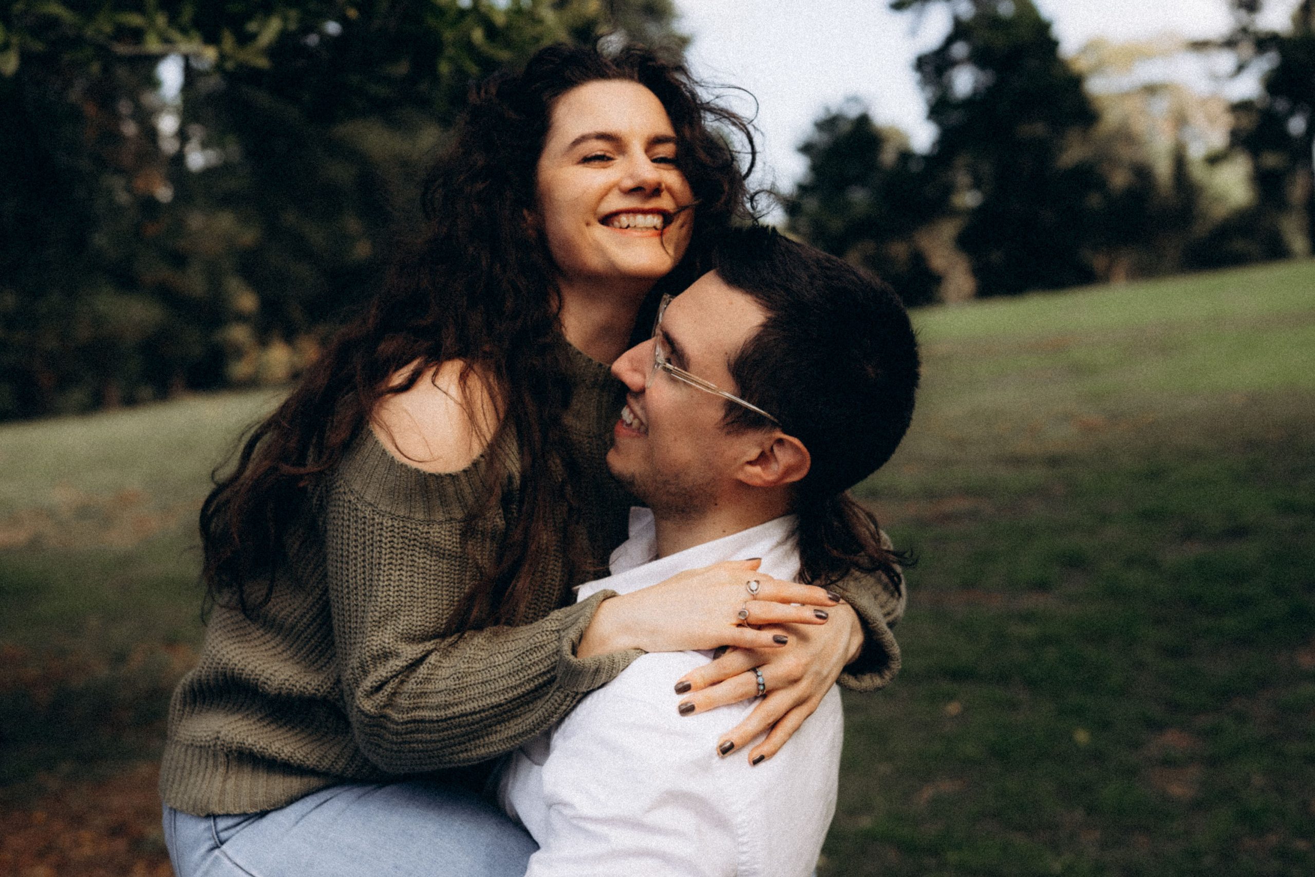 Summer beach getaway photos of couple in love piggyback happy happiness jewellery glasses hug hugging field trees grass grassy